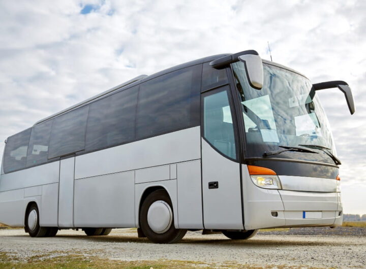 Un autocar de tourisme moderne et blanc stationné sur un terrain dégagé, illustrant comment obtenir un devis pour la location d'un autocar.