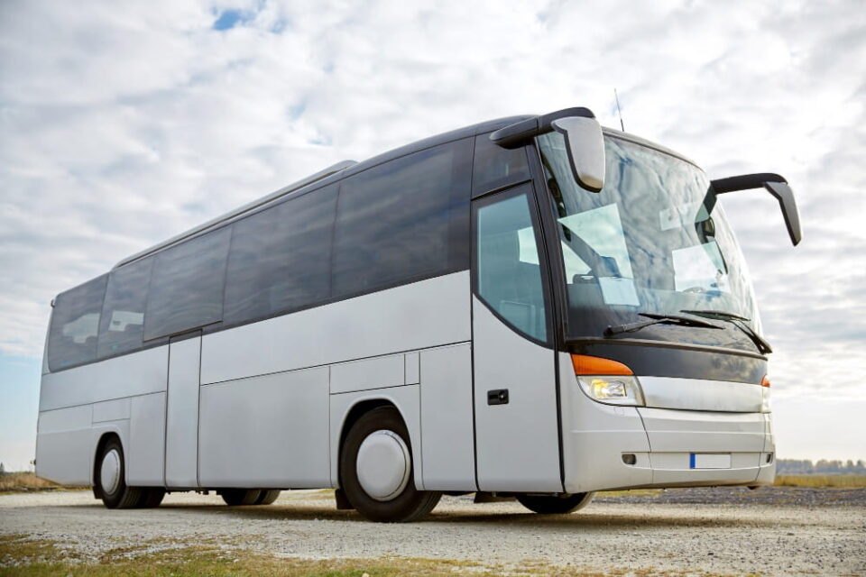 Un autocar de tourisme moderne et blanc stationné sur un terrain dégagé, illustrant comment obtenir un devis pour la location d'un autocar.