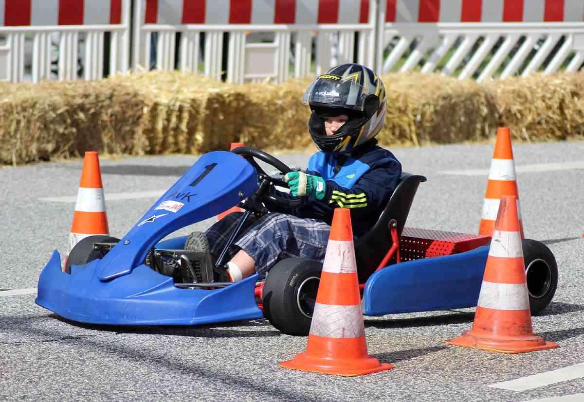 Enfant pilotant un kart bleu sur une piste de course miniature Enfant pilotant un kart bleu sur une piste de course miniature