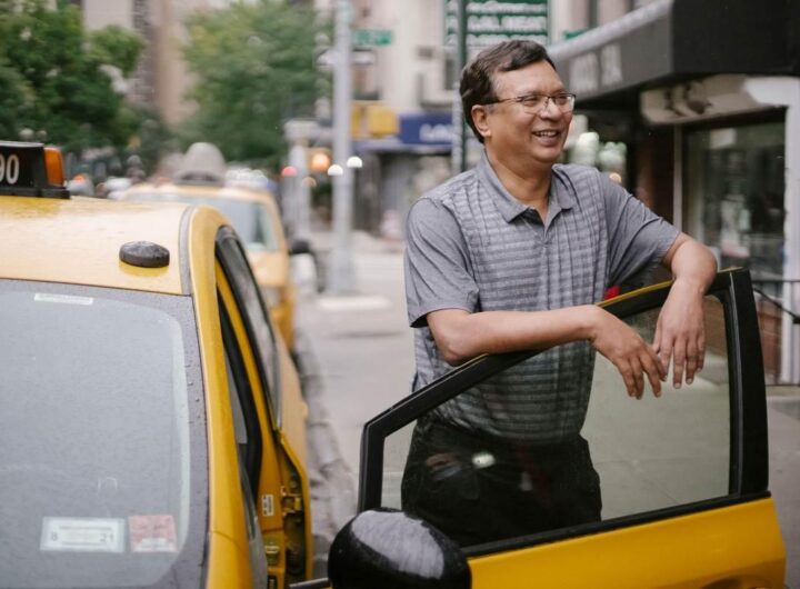 Un homme souriant repose la main sur la portière d'un taxi