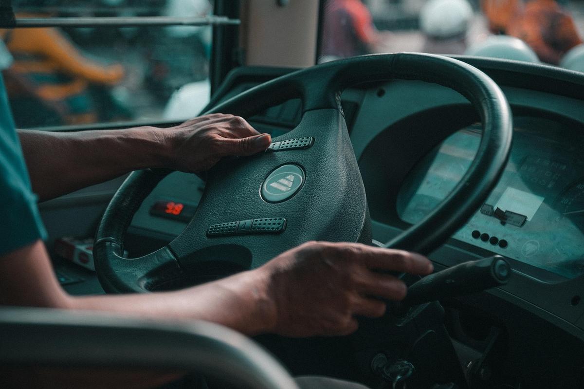 Un conducteur tient le volant avec les deux mains à l'intérieur d'un bus Un conducteur tient le volant avec les deux mains à l'intérieur d'un bus