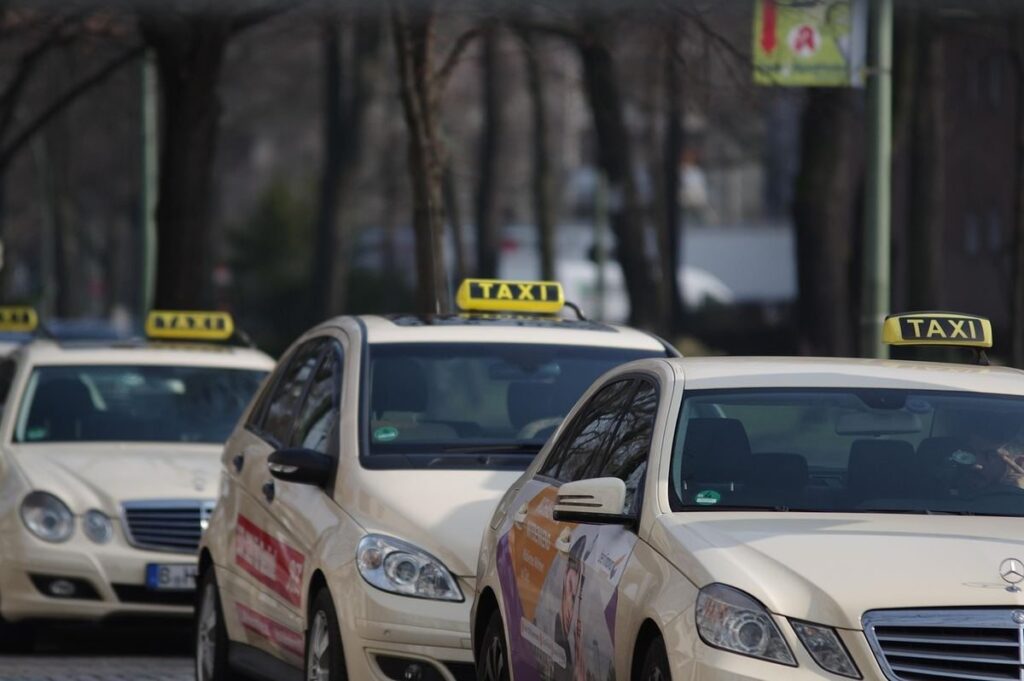 Des voitures-taxis alignées sur une rue, panneaux lumineux visibles