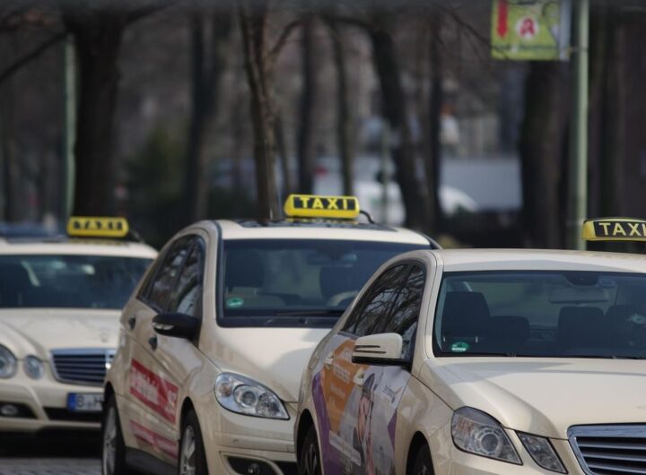 Des voitures-taxis alignées sur une rue, panneaux lumineux visibles
