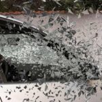 Vitre de voiture explosée, éclats de verre en vol, mur en arrière-plan