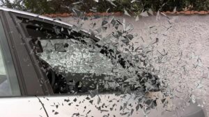 Vitre de voiture explosée, éclats de verre en vol, mur en arrière-plan