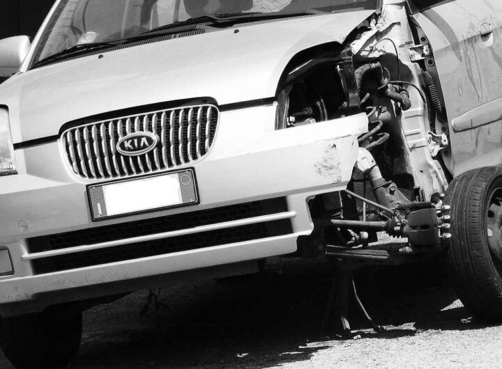 Voiture Kia blanche après choc frontal, moteur visible, roue avant droite absente