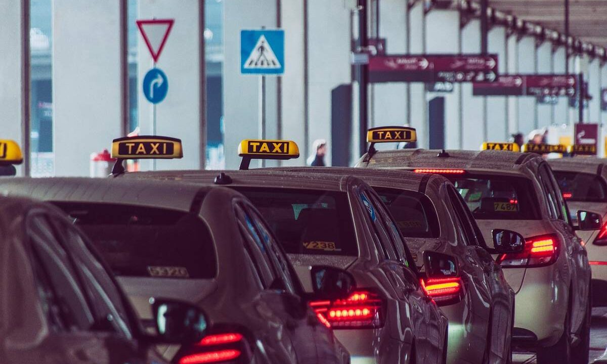 Des taxis alignés devant un bâtiment avec panneaux routiers