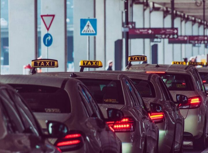 Des taxis alignés devant un bâtiment avec panneaux routiers