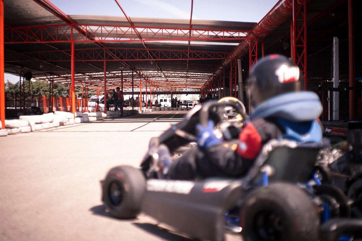 Conducteur en kart sur piste couverte, portant casque et gants