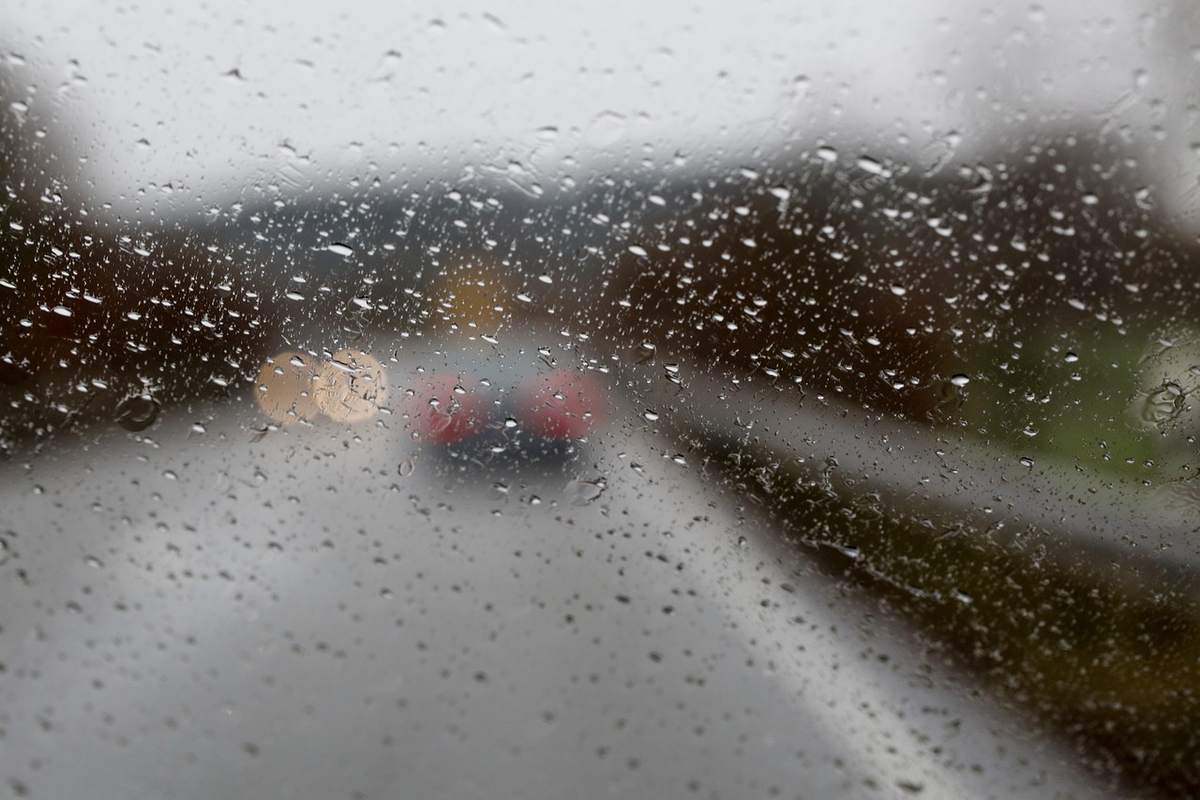Gouttes d'eau recouvrent le pare‑glace, une voiture passe sur la route