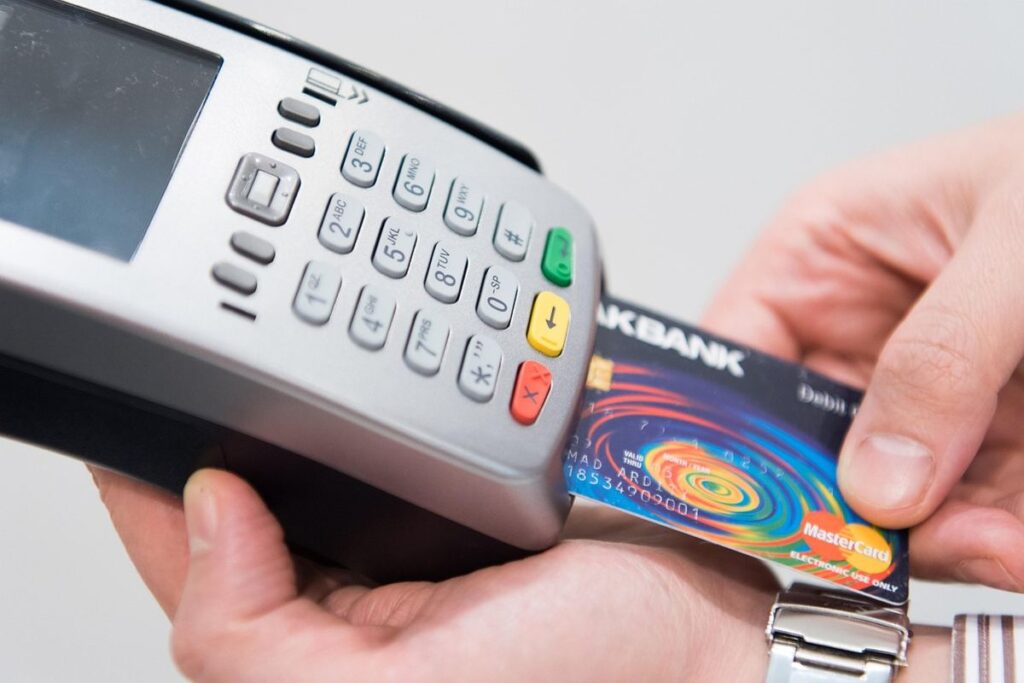 Une main insère une carte bancaire dans un terminal de paiement
