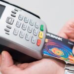 Une main insère une carte bancaire dans un terminal de paiement